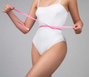 woman measuring her waist using pink tape measurement