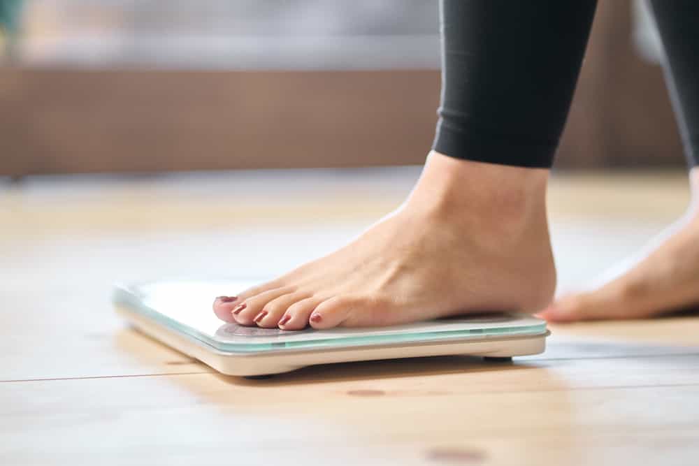 feet of a woman stepping on a weighing scale